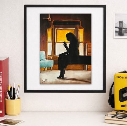 A framed art print depicting a woman's silhouette sitting on a bench in front of a glowing window, styled on a white shelf next to books, a yellow Sony Walkman, and glasses. Inspired from felicity porter 90’s -2000 tv series.