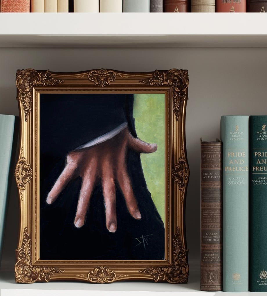 A framed original oil painting of a hand resting on a dark surface, displayed on a white bookshelf next to books. The painting is enclosed in an ornate gold frame, and the text 'Original Oil Painting' appears at the bottom.