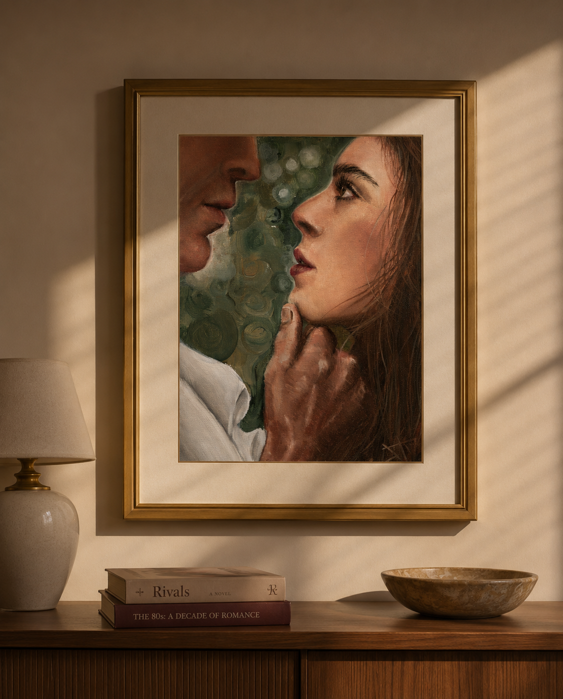 A framed portrait painting of a man and woman facing each other, displayed on a beige wall above a wooden console table with a lamp, books, and a bowl.